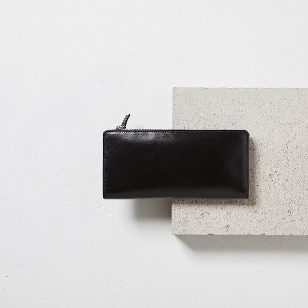 Status Anxiety Black Dakota Wallet on a cement block styled shot