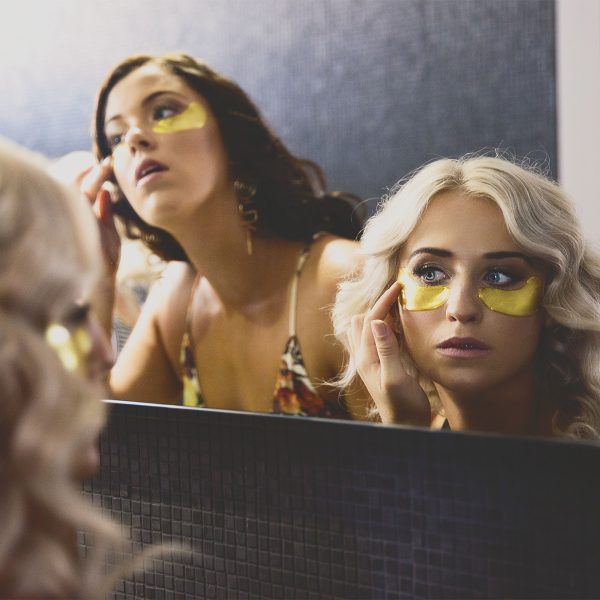 two ladies looking in a mirror wearings Perfecting Active Gold Eye Mask