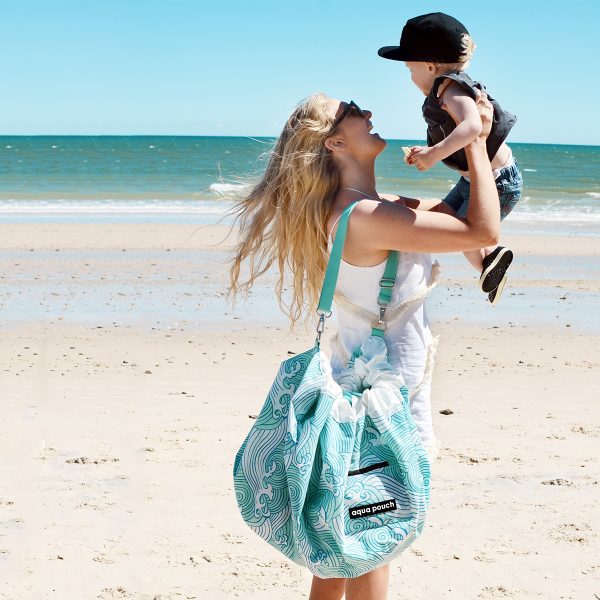 women holding child on beach with a Aqua Waterproof Play Pouch