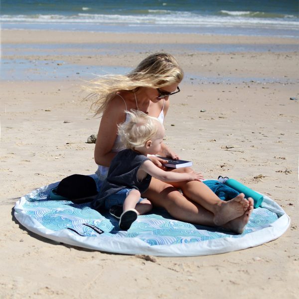 women with child on the beach reading on a Aqua Waterproof Play Pouch