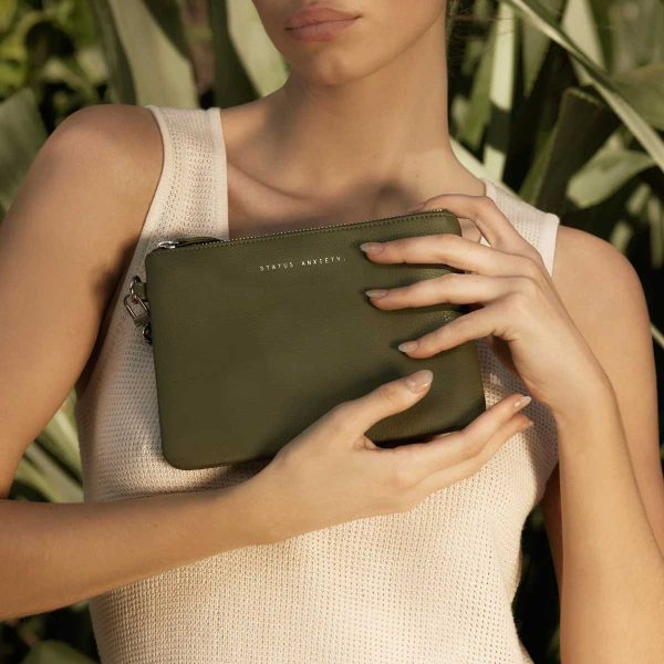 woman holding the green status anxiety clutch- fixation